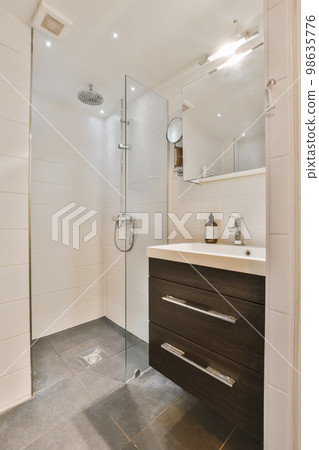 a modern bathroom with white tiles and dark wood cabinet under the sink is in front of the shower stall door 98635776