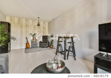 a living room with wood flooring and white walls, including a black coffee table in the center of the room a living room with wood flooring and white walls, including a black coffee table in the center of the room 98636179