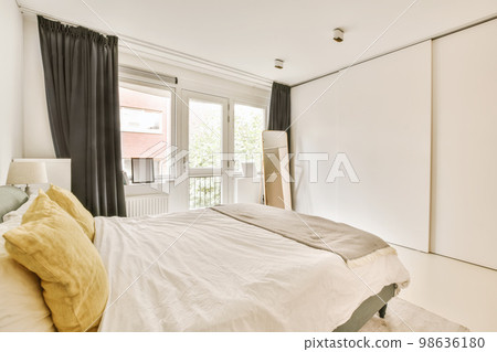 a bedroom with white walls and black drapes on the bed is next to an open window that looks out onto the street 98636180