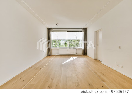 an empty room with wood floors and white walls, there is a large window in the wall to the right an empty room with wood floors and white walls, there is a large window in the wall to the right 98636187