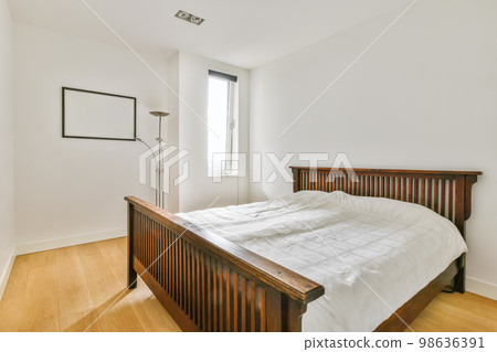 a bedroom with white walls and wood flooring on the bed, there is a large window in the room 98636391