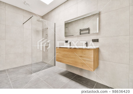 a modern bathroom with white tiles and grey flooring on the walls, there is a large mirror above the sink a modern bathroom with white tiles and grey flooring on the walls, there is a large mirror above the sink 98636420