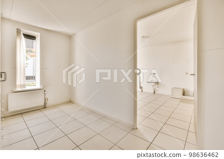 an empty room with white tile flooring and large open door leading to the bathroom area in this apartment building 98636462