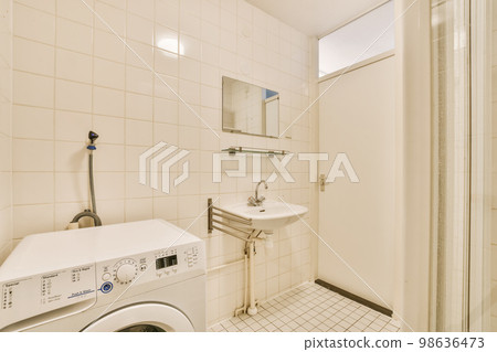 a laundry room with a washer and dryer in the corner, which is white tile on the floor 98636473