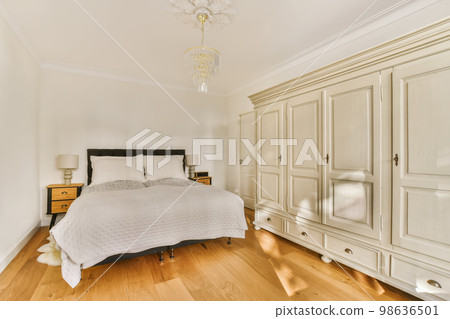 a bedroom with white walls and wood flooring in the middle of the room, there is a chandel on the bed a bedroom with white walls and wood flooring in the middle of the room, there is a chandel on the bed 98636501