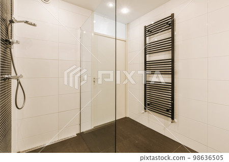 a modern bathroom with black and white tiles on the walls, along with a glass shower stall in the corner 98636505