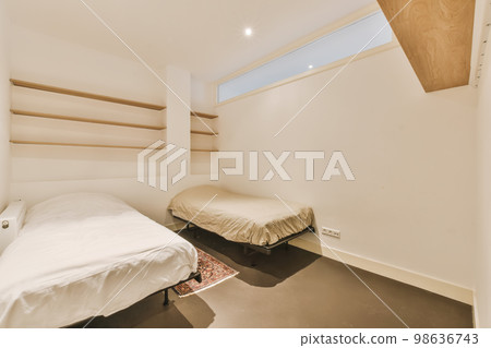 a small bedroom with two beds and shelves on the wall behind it, there is a window that looks out to the outside 98636743