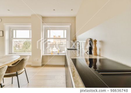 a kitchen and dining area in a modern apartment with white walls, hardwood flooring and large windows overlooking the city a kitchen and dining area in a modern apartment with white walls, hardwood flooring and large windows overlooking the city 98636748