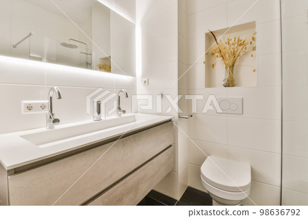 a modern bathroom with white walls and black flooring the sink is in front of the mirror on the wall 98636792
