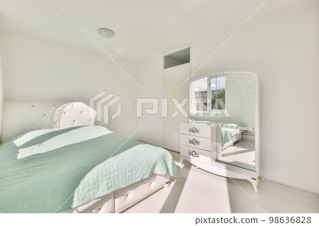 a bedroom with a bed, dresser and mirror on the wall in front of the room is very clean white 98636828