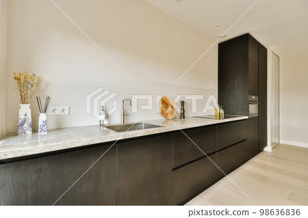 a modern kitchen with black cabinets and white countertops in the center of the room is a large mirror on the wall a modern kitchen with black cabinets and white countertops in the center of the room is a large mirror on the wall 98636836