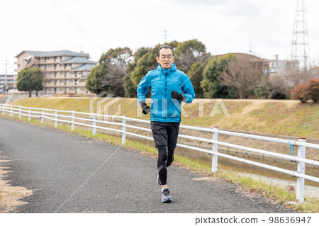 One middle-aged man jogging on the promenade along the river as a hobby One middle-aged man jogging on the promenade along the river as a hobby 98636947