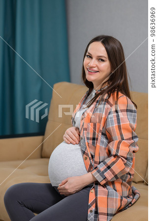 Pregnant woman rests on cozy sofa expecting child birth 98636969