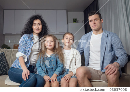 Family sits on sofa and demonstrates beautiful smiles 98637008