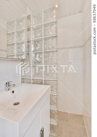 a white bathroom with glass blocks on the wall behind it and a mirror in the shower stall to the right a white bathroom with glass blocks on the wall behind it and a mirror in the shower stall to the right 98637049