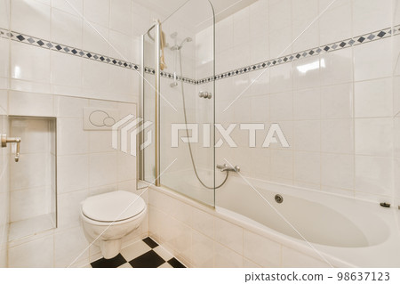 a white bathroom with black and white tiles on the floor, shower stall and toilet in the corner of the room 98637123
