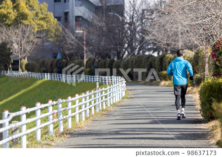 One middle-aged man jogging on the promenade along the river as a hobby 98637173
