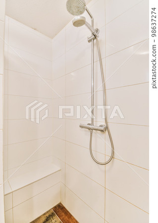 a shower with white tiles on the walls and wood flooring in a small bathroom area that is very clean 98637274