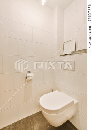 a white toilet in a bathroom with tile on the floor and wall behind it is a shelf above the toilet a white toilet in a bathroom with tile on the floor and wall behind it is a shelf above the toilet 98637276
