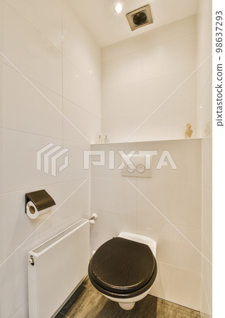 a toilet in a bathroom with white tiles on the walls and wood flooring around the toilet bowl is black a toilet in a bathroom with white tiles on the walls and wood flooring around the toilet bowl is black 98637293