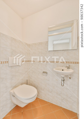 a bathroom with tile flooring and white tiles on the walls, there is a mirror above the toilet bowl a bathroom with tile flooring and white tiles on the walls, there is a mirror above the toilet bowl 98637342