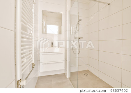 a modern bathroom with white tile walls and flooring, including a walk - in shower stall on the right side 98637402