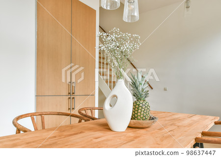Interior of the dining area next to the stairs to the top and a vase of flowers on the table 98637447
