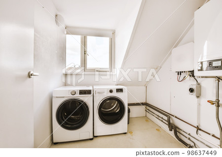 a small laundry room with washer and dryer in the corner on the left is a window to the right 98637449