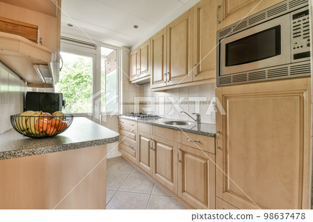 a kitchen with wood cabinets and granite counter tops on the island in front of the sink is an orange bowl filled with fruit a kitchen with wood cabinets and granite counter tops on the island in front of the sink is an orange bowl filled with fruit 98637478