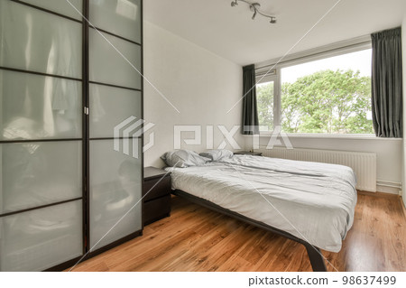a bedroom with wood flooring and sliding glass doors on the wall to the right is a large bed in front a bedroom with wood flooring and sliding glass doors on the wall to the right is a large bed in front 98637499