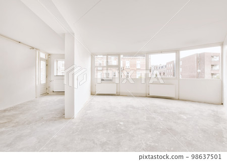 an empty room with white walls and floor to the right, there is a large window that looks out onto the street 98637501