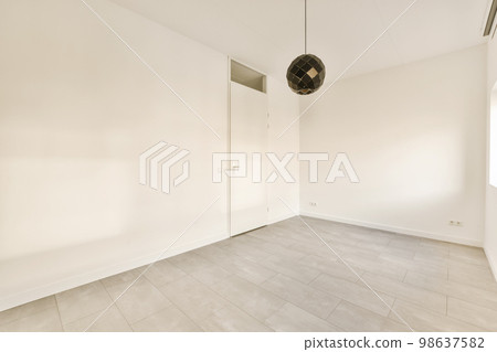 an empty room with white walls and wood flooring, there is a fan on the wall in the corner 98637582