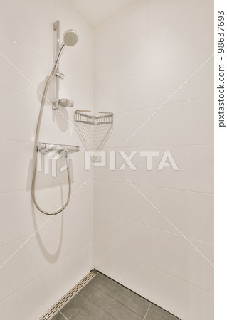 a shower in a white tiled bathroom with grey tile flooring and wall mounted handrails on the walls 98637693