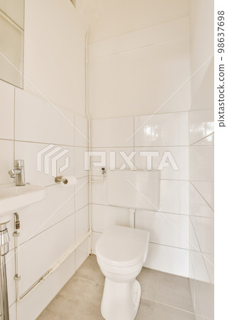 a bathroom with white tiles on the walls, and a toilet in the corner next to the sink is visible 98637698