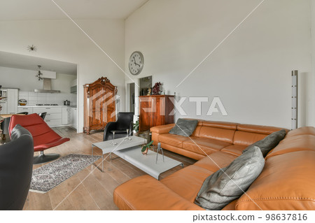 a living room with orange leather couches and an old clock on the wall in the room is very clean 98637816