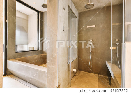 Shower faucets attached to tiled wall near glass partition and ornamental curtail in washroom at home 98637822