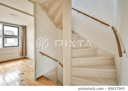 an empty room with wood flooring and white painted staircase leading up to the second floor in a home for sale 98637965