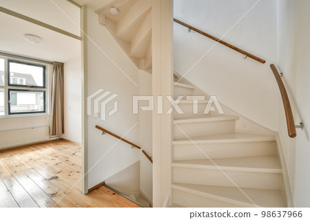 an empty room with wood flooring and white painted staircase leading up to the second floor in a home for sale 98637966