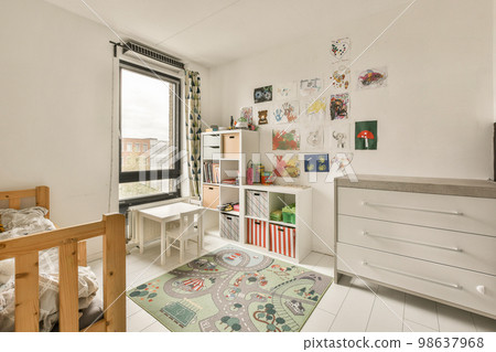 a child's room with a bed, dresser and toy car on the floor in front of the window 98637968