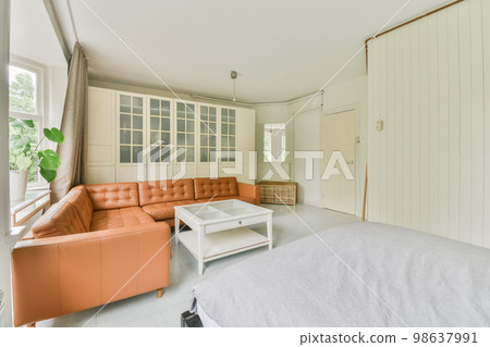 a living room with an orange couch and white bed in the photo is taken from the front door to the bedroom 98637991