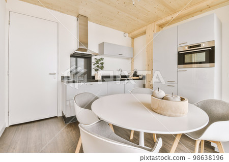 Home interior design of modern loft apartment with open kitchen in minimalist style and spacious dining zone with table and chairs Home interior design of modern loft apartment with open kitchen in minimalist style and spacious dining zone with table and chairs 98638196