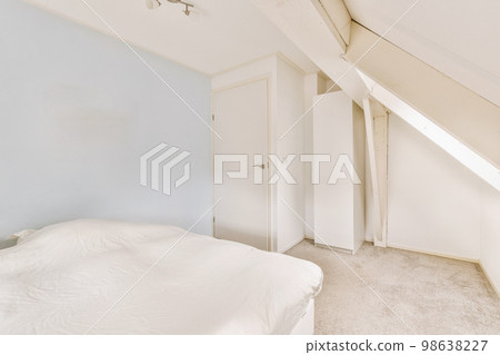 Home interior design of bedroom with bed and wooden wardrobe placed in corner near window in modern apartment 98638227