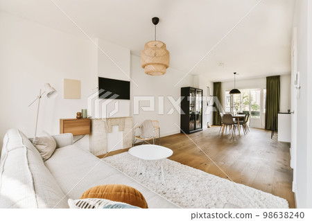 a living room with wood flooring and white walls, an area rug is placed on the floor in front of the couch a living room with wood flooring and white walls, an area rug is placed on the floor in front of the couch 98638240