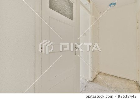 Light narrow hallway with many doors in white walls and shabby floor 98638442