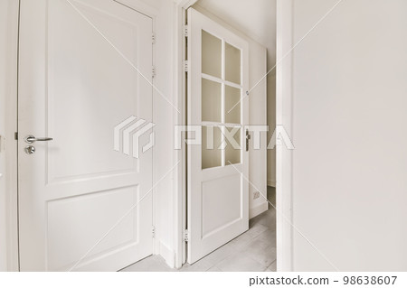 an empty room with two doors and one door opened to reveal the other rooms in the apartment has white walls an empty room with two doors and one door opened to reveal the other rooms in the apartment has white walls 98638607