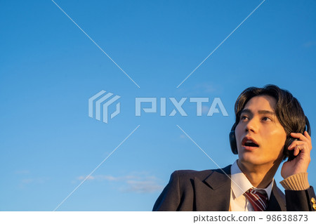 High school student listening to music with headphones English listening uniform blazer blue sky subscription surprised High school student listening to music with headphones English listening uniform blazer blue sky subscription surprised 98638873
