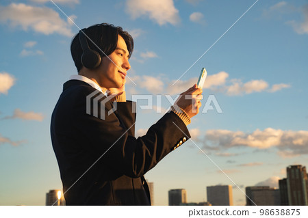 戴耳機聽音樂的高中生英語聽力製服西裝外套藍天訂閱智能手機 98638875