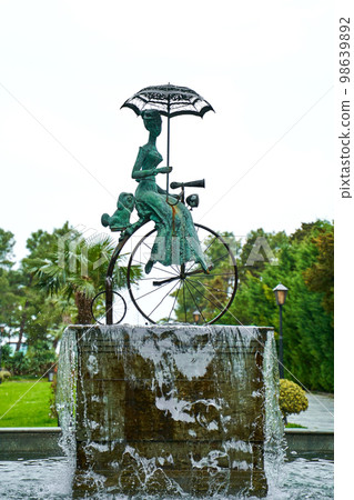 Fountain with a sculpture of a girl with a dog on a circus bike Fountain with a sculpture of a girl with a dog on a circus bike 98639892