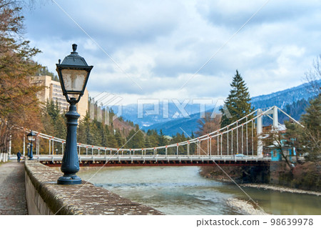 Crp plan of the light lantern on the embankment along the mountain river. Mountains and trees in the background 98639978