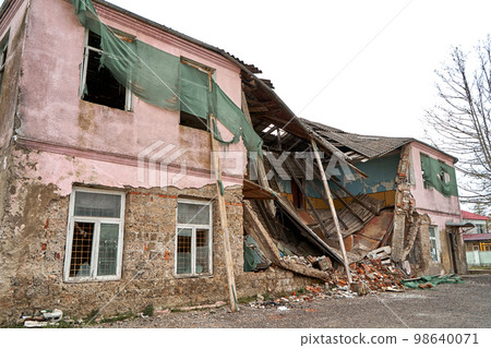An abandoned two-story building with a crumbling roof An abandoned two-story building with a crumbling roof 98640071